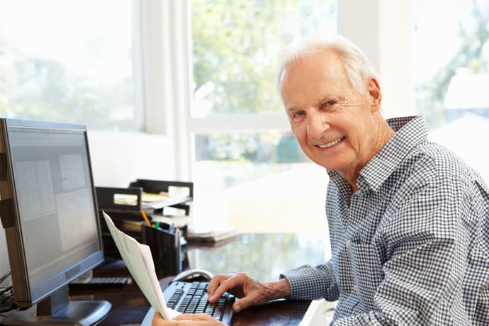 Senior man sits at computer
