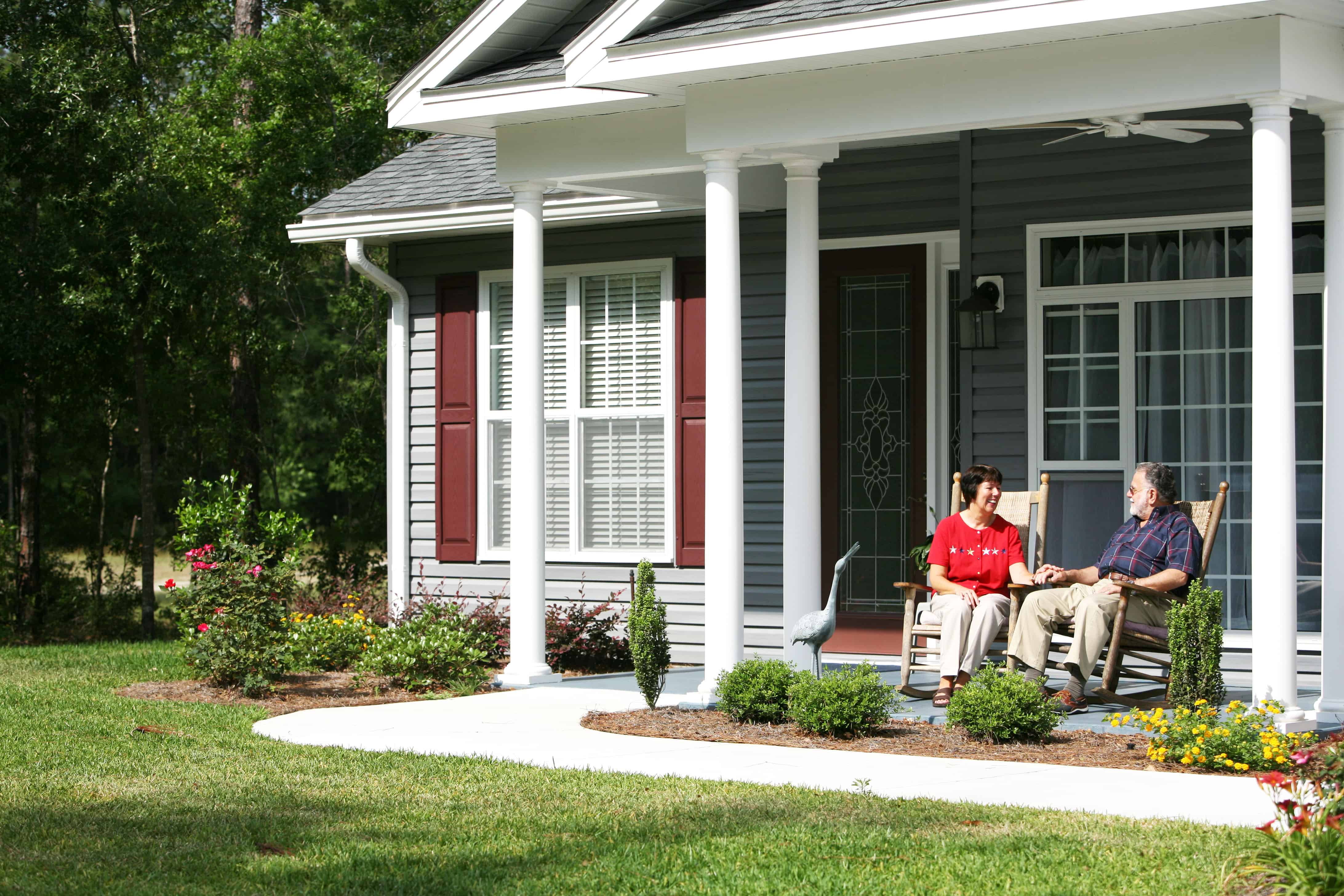 Older adult couple in rocking chairs on the front porch of their home