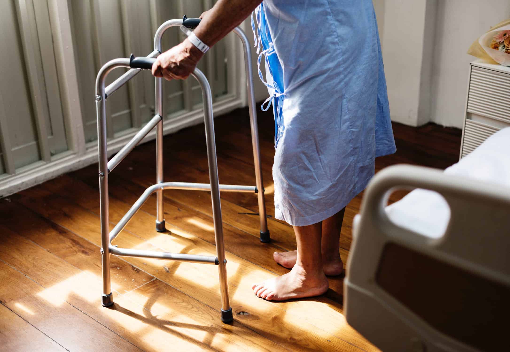 Senior adult hospital patient using a walker to slowly move about the room