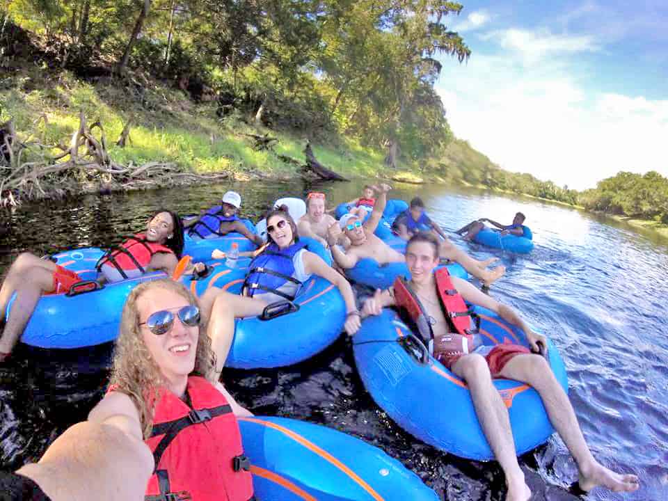 Youth camp floating in bright blue inner tubes down a river at Camp Suwannee