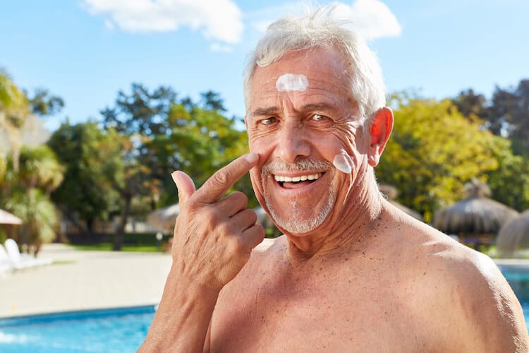 senior man putting on sunscreen