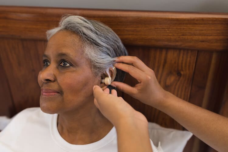 Senior woman gets fitted for a hearing aid.