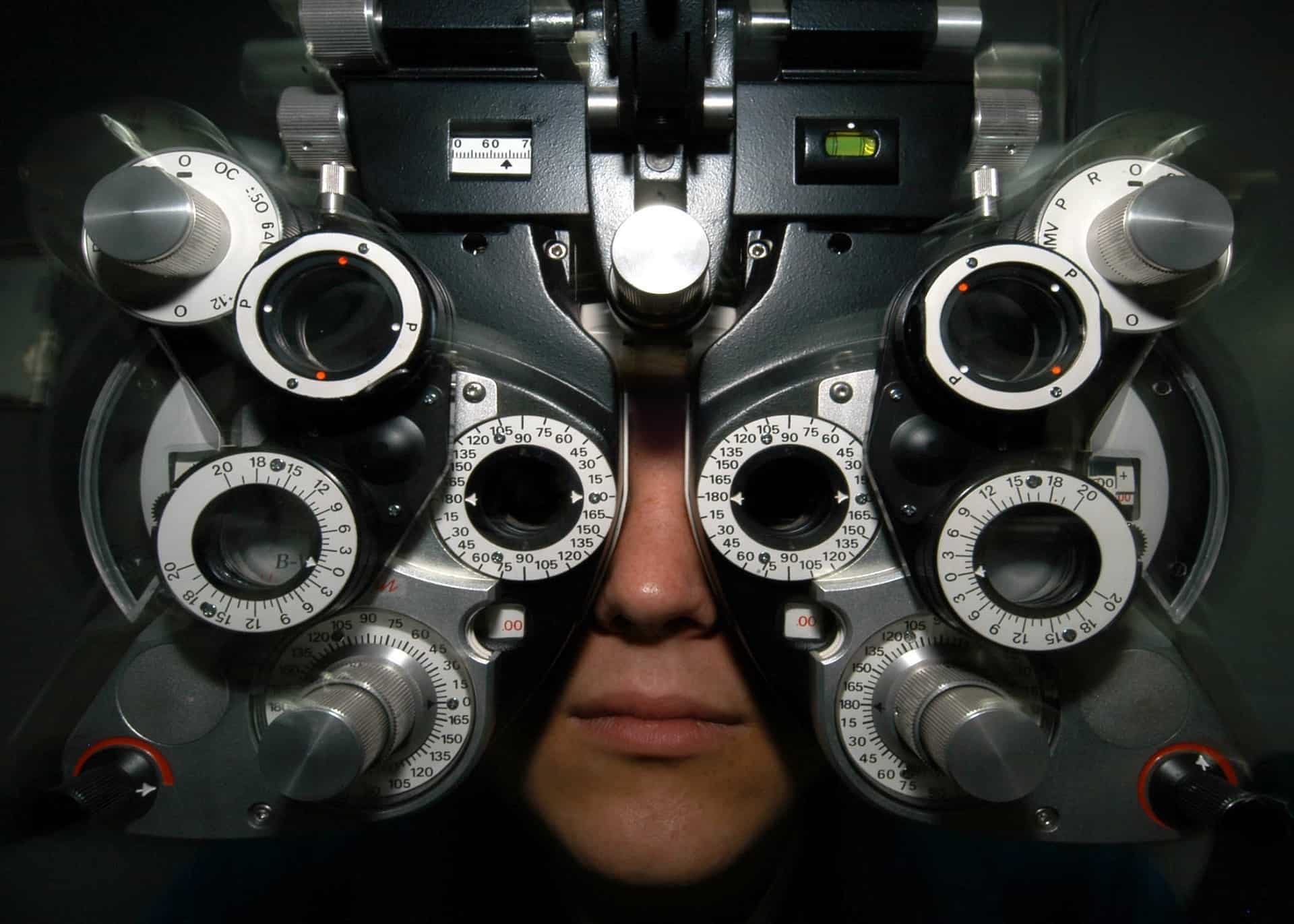 Man looking through an phoropter (instrument with numerous lenses and dials)