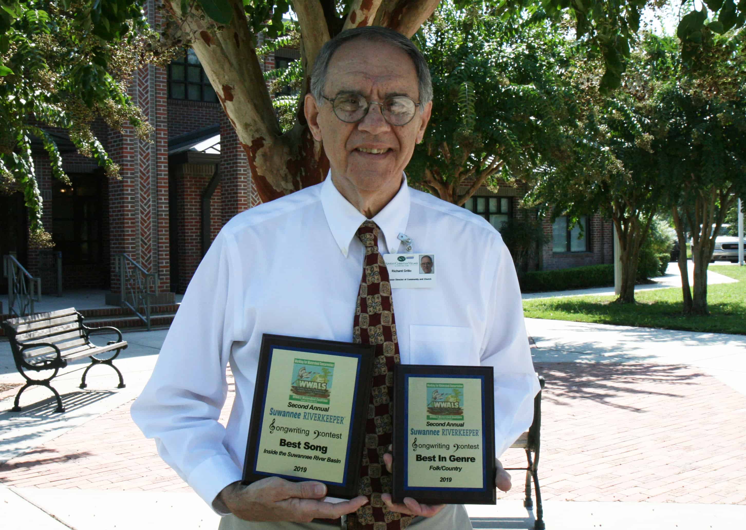 Dick Grillo, ACV sr. director of church and community relations holding two awards in recognition of his songwriting talent