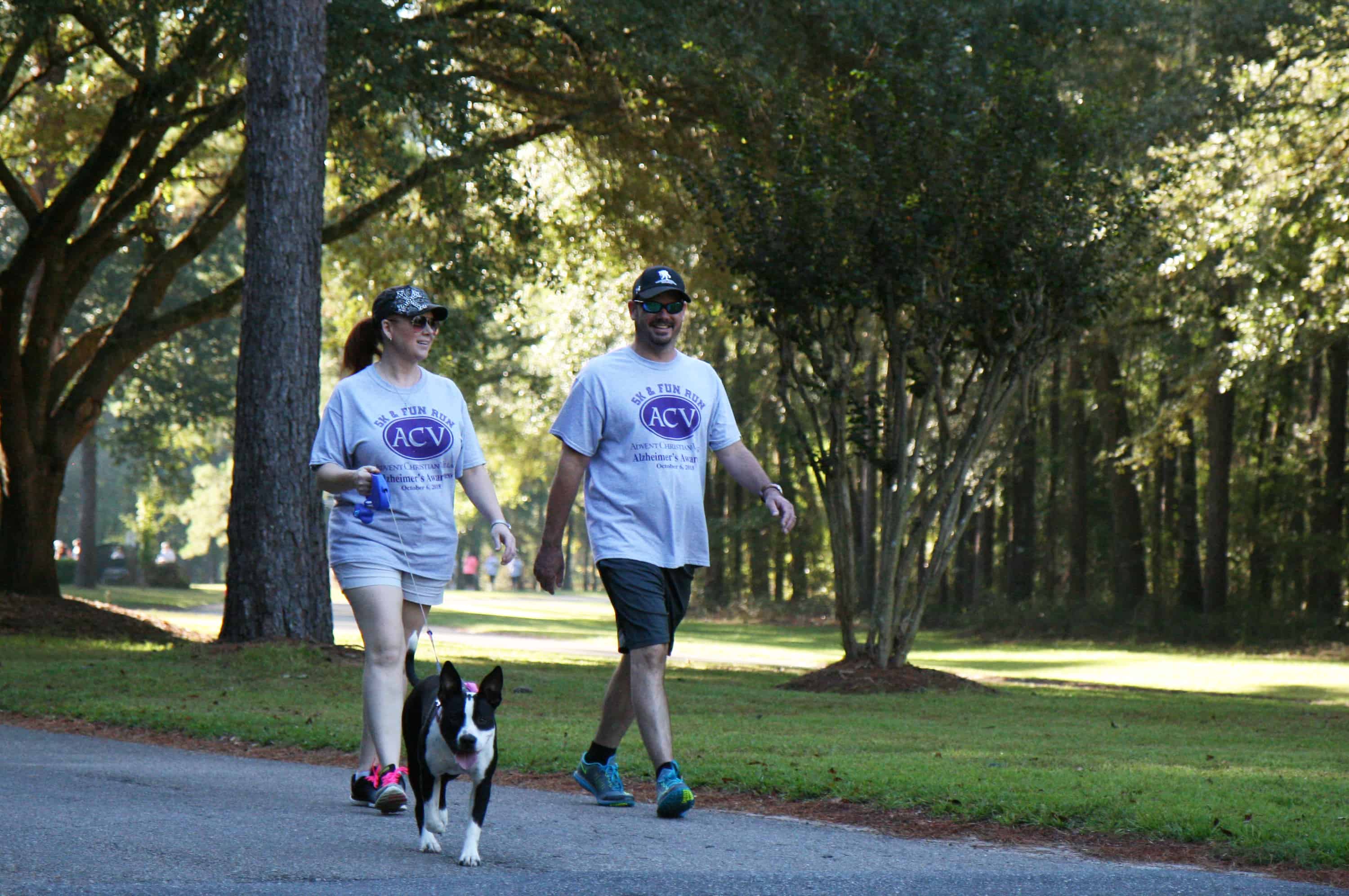Two people walking a 5K with a dog through the park