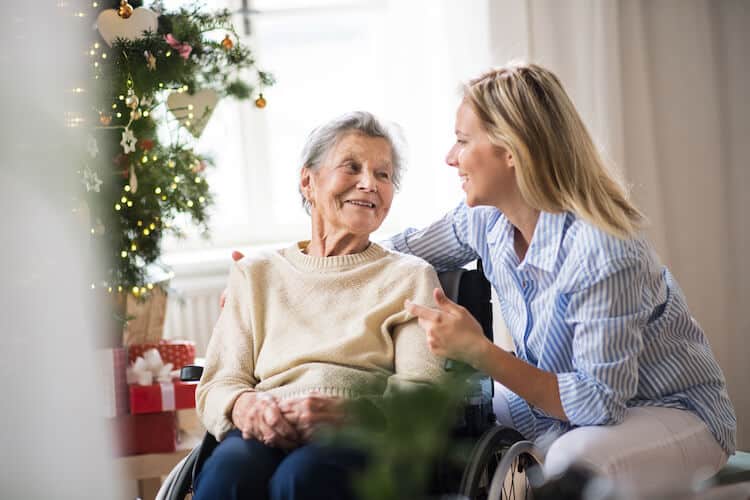 A caregiver sits with her senior parent during the holiday season.