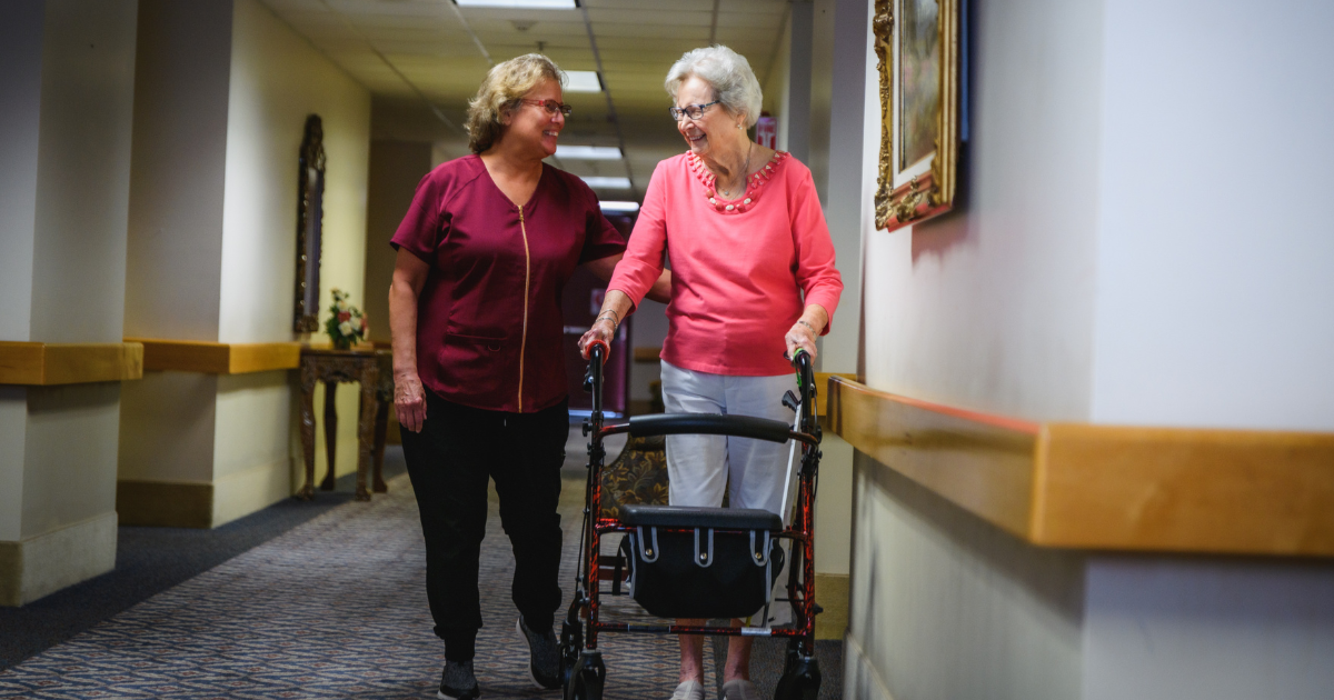 An image of an older adult woman using a walker and her caretaker to show the benefits of assisted living.