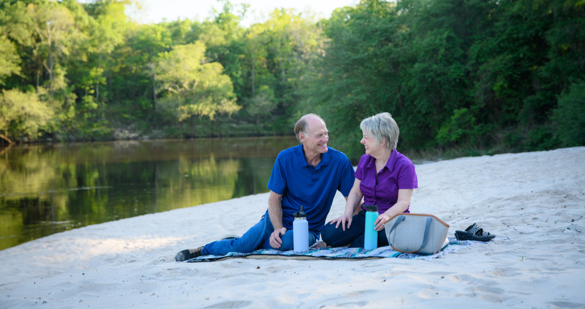 A man and a woman enjoying a picnic by a river
