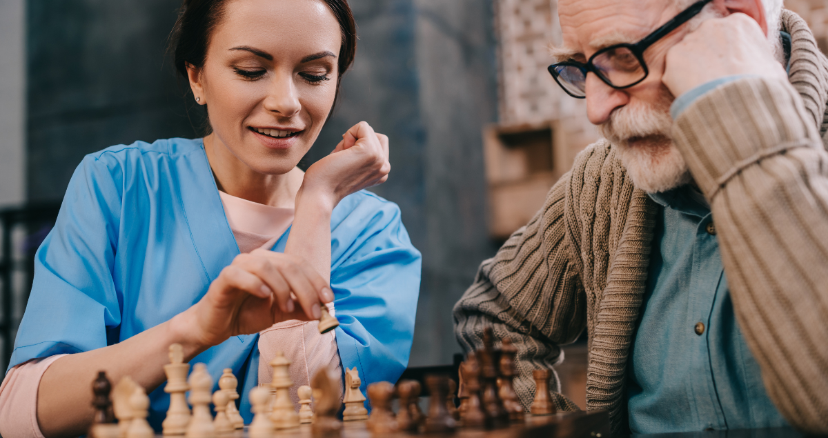 A nurse and an elderly man playing chess